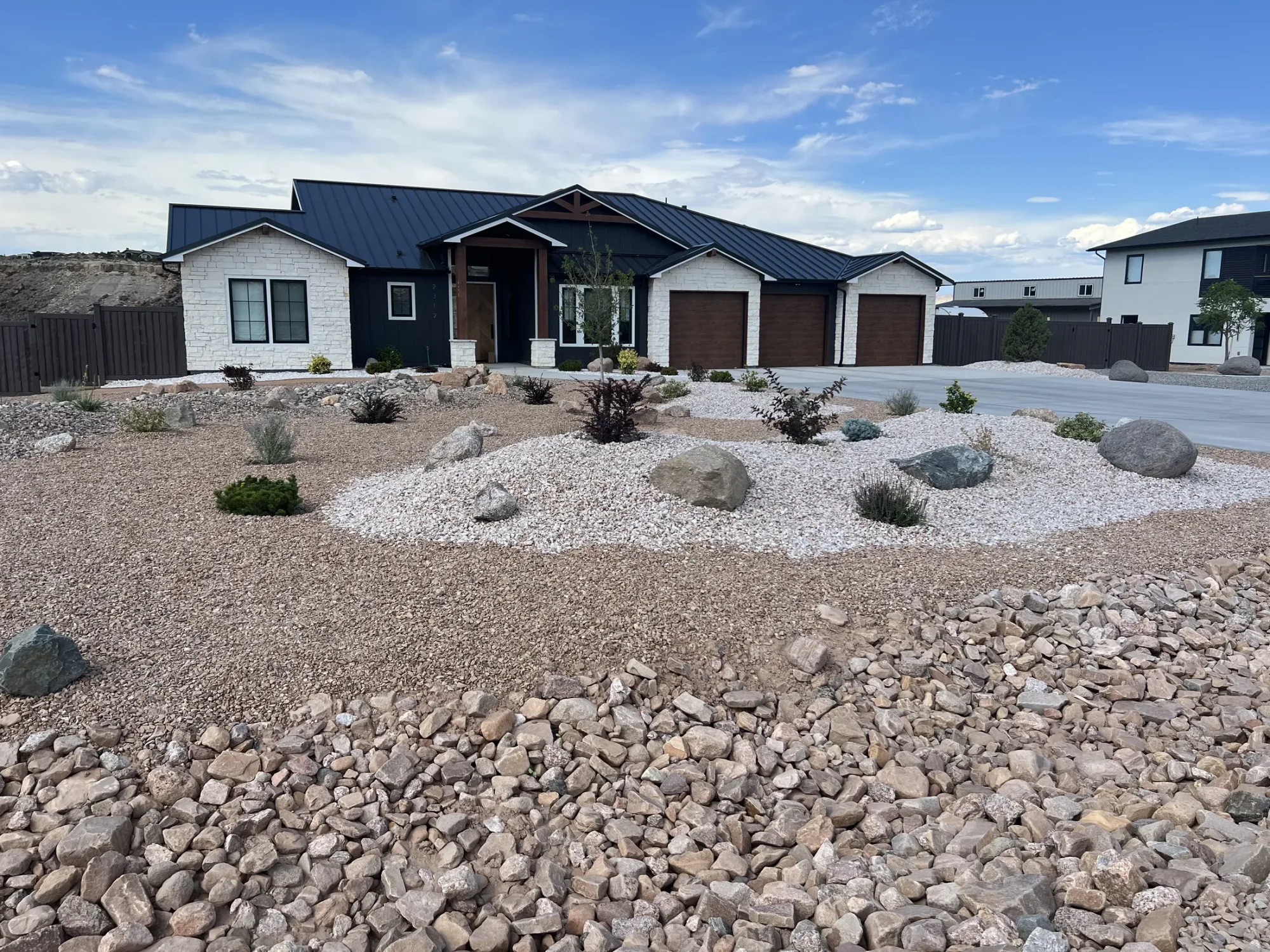 Recent xeriscape project with sculpted rock beds and drought-tolerant planting.